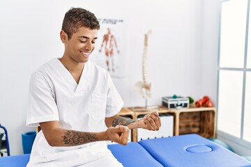 Sticker - Young hispanic man working as physiotherapist holding small balls at physiotherapy room