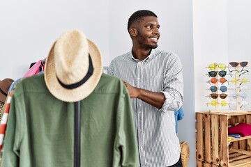 Wall Mural - Young african american man smiling confident choosing clothes at clothing store