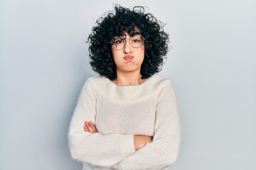 Sticker - Young middle east woman with arms crossed gesture puffing cheeks with funny face. mouth inflated with air, catching air.