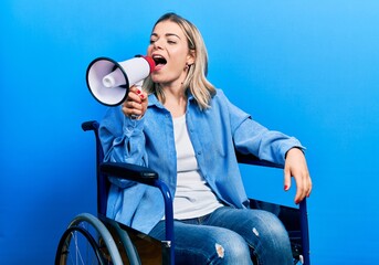 Blonde woman sitting on wheelchair screaming through megaphone over isolated background