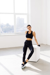 Wall Mural - Young woman sitting on a box at gym after her workout. Female athlete taking rest after exercising at gym.