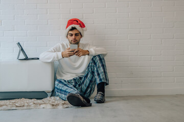Wall Mural - man at home with santa claus hat with mobile phone and computer