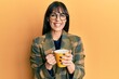 © Krakenimages.com - Young hispanic woman wearing business style drinking cup of coffee looking positive and happy standing and smiling with a confident smile showing teeth