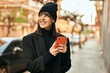 © Krakenimages.com - Young hispanic woman smiling happy using smartphone at the city.