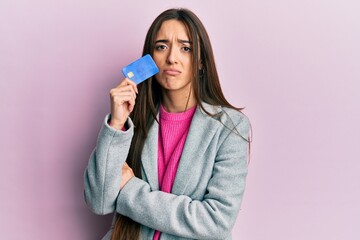 Sticker - Young hispanic girl holding credit card depressed and worry for distress, crying angry and afraid. sad expression.