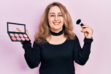 Poster - Middle age caucasian woman holding makeup brush and blush smiling with a happy and cool smile on face. showing teeth.