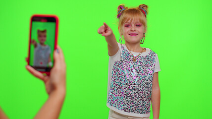 Happy funky young female blogger child kid girl, recording funny dancing video on smartphone for social network or personal channel, having fun entertaining on weekend at home on chroma key background