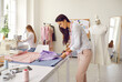 © Studio Romantic - Female designer or tailor work with fabric sew garment or clothing piece in small atelier. Woman seamstress or designer work with textiles design clothes at workshop. Style and fashion, dressmaking.