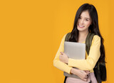 Fototapeta  - Happy young university student girl holding laptop computer with smile face carrying backpack Pretty asian woman stand over yellow background and copy space Beauty female look at camera with happiness