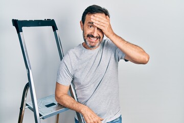 Sticker - Middle age hispanic man using ladder stressed and frustrated with hand on head, surprised and angry face