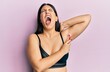 Beautiful brunette woman shaving armpit hair with razor angry and mad screaming frustrated and furious, shouting with anger looking up.