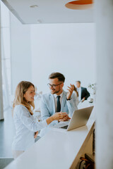 Poster - Young business couple working and discussing by laptop in the office