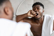 © Prostock-studio - Sleepy African American Man Yawning Standing Near Mirror In Bathroom