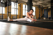 © ty - Young sporty woman stretching at the gym.