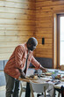 © pressmaster - Young African man putting homemade cooked food on festive table prepared for family dinner in living-room