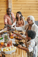 Wall Mural - Cheerful family members toasting with drinks over table served with homemade food prepared for festive dinner