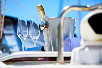 Wall Mural - Romantic luxury evening on cruise yacht with champagne setting. Empty glasses and bottle with champagne and tropical sunset with sea background