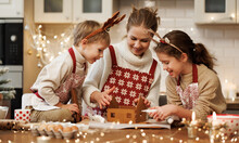 Happy Family Mother And Two Kids In Xmas Aprons Decorating Christmas Honey Gingerbread House