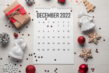 Paper Calendar For December 2022, Christmas Decor And Confetti On Light Wooden Background