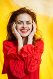 Fototapeta Tęcza - smiling woman in red dress posing yellow background