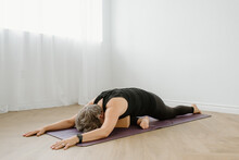 Woman In Pigeon Pose On Yoga Mat At Home