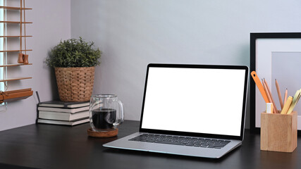 Home office desk with computer laptop, coffee cup, potted plant and pencil holder.