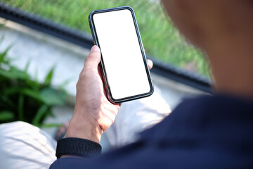 Wall Mural - over shoulder view of young man using smart phone while sitting in the garden.