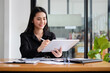 © wattana - Smiling beautiful businesswoman holding stylus pen and writing information on digital tablet.