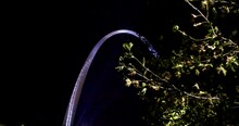 The Gateway Arch In St. Louis, Missouri At Night Using Gimbal Video Moving Forward With Trees In Foreground.