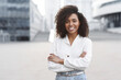 Leinwandbild Motiv Young businesswoman in a city looking at camera, African american student girl portrait, Young woman with crossed arms smiling, People, enjoy life, student lifestyle, city life, business concept