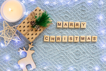 Wall Mural - Christmas blue background, with a shining garland, with wooden letters with the inscription Merry Christmas