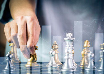 Hand businessman moving the golden knight chess fighting silver knight with fire sparks chess on chess board to successfully in the competition. Management or leadership strategy and teamwork concept.