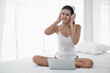 © u photostock - Asia woman sitting on the bed in morning with headphone and laptop