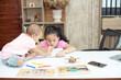 © rachaphak - Little toddler girl sit on the working table, her older sister sitting and playing together while mother not home