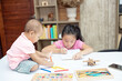 © rachaphak - Little toddler girl sit on the working table, her older sister sitting and playing together while mother not home
