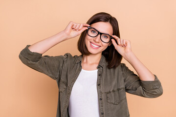 Poster - Photo of cheerful lady hold eyeglasses beaming smile wear khaki shirt isolated beige color background