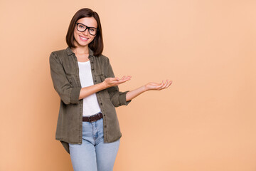 Poster - Photo of reliable lady hands demonstrate empty space wear specs khaki shirt isolated beige color background