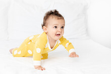Funny Baby Crawling On White Bed Sticking Tongue