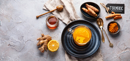 Wall Mural - Healthy turmeric golden tea on light gray background.