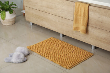 Poster - Soft orange bath mat and slippers on floor indoors