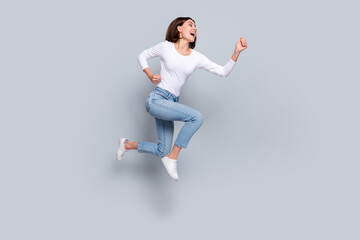 Sticker - Photo of charming pretty lady dressed white clothes smiling running fast looking empty space jumping high isolated grey color background