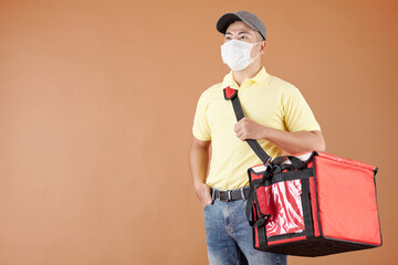 Portrait of Asian courier in protective mask holding delivery bag