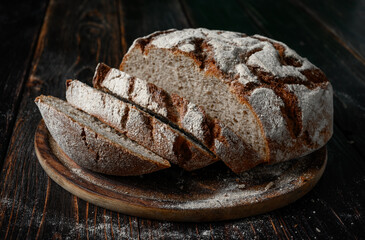 Homemade rye bread. Rye bread in a round shape on a wooden background in a rustic style with bread knife and sliced. Top view.