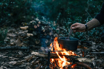 vintage camping kettle over open fire in summer forest, close-up.