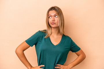 Wall Mural - Young caucasian woman isolated on beige background confused, feels doubtful and unsure.