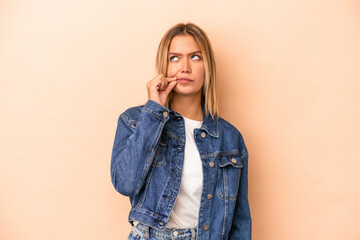 Wall Mural - Young caucasian woman isolated on beige background with fingers on lips keeping a secret.