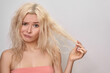 Beautiful woman with messed up hair. Unhappy grimacing face. Blond bleaching hairstyle with problem brittle hair
