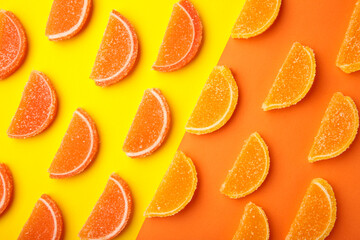 Delicious orange and lemon marmalade candies on yellow background, flat lay