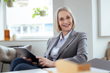 Smiling Businesswoman Holding Tablet PC In Office