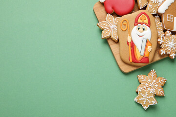 Wall Mural - Tasty gingerbread cookies on green background, flat lay with space for text. St. Nicholas Day celebration